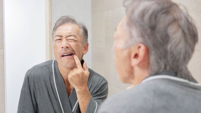 muž kontrolující si zuby