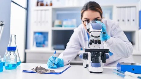 Žena v laboratoři koukající do mikroskopu