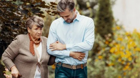 Muž podpírající seniorku s Alzheimerem