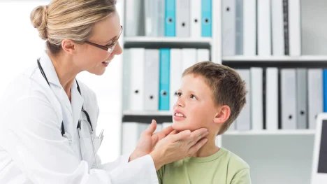 Lékařka vyšetřující příušní žlázy malého kluka