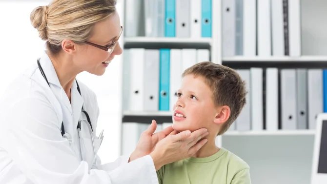 Lékařka vyšetřující příušní žlázy malého kluka